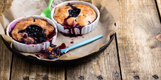 Individual blueberry pies on a rustic wooden table.