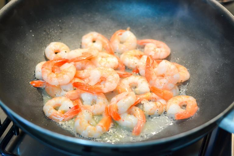 Shrimp Stir-Fry with Tomatoes, Avocado, and Garlic deveined shrimp frying in a hot wok